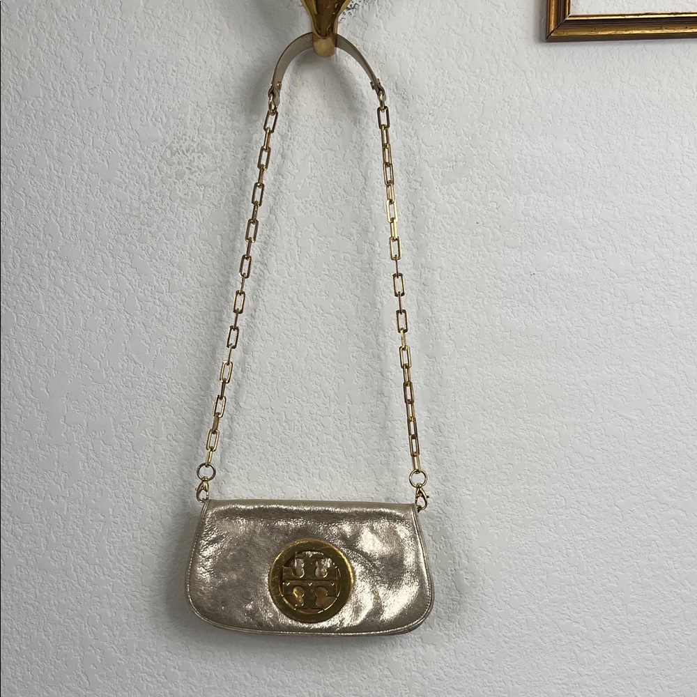 The Reva Metallic Clutch is defined by a curved shape and bold hardware. Wear it